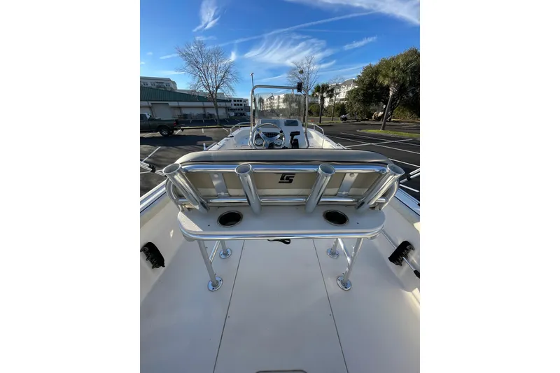 Slide: The Image of 2023 Carolina Skiff 21 LS boat interior with rod holders and console, parked outdoors. - 11