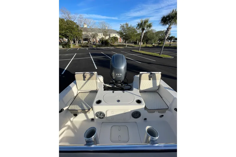 Slide: The Image of 2023 Carolina Skiff 21 LS boat interior with seating and motor in a parking lot. - 7