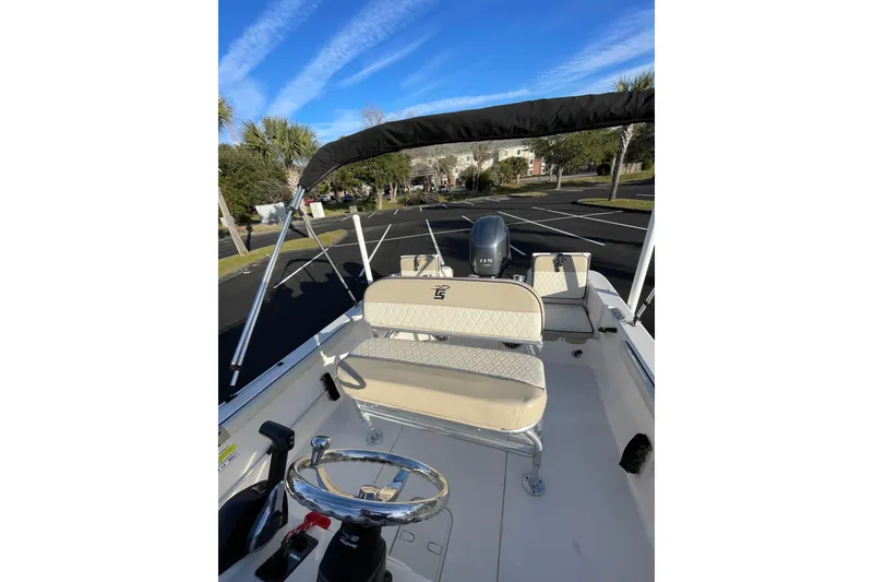 Slide: The Image of 2023 Carolina Skiff 21 LS boat interior with steering wheel and seating, parked outdoors. - 8