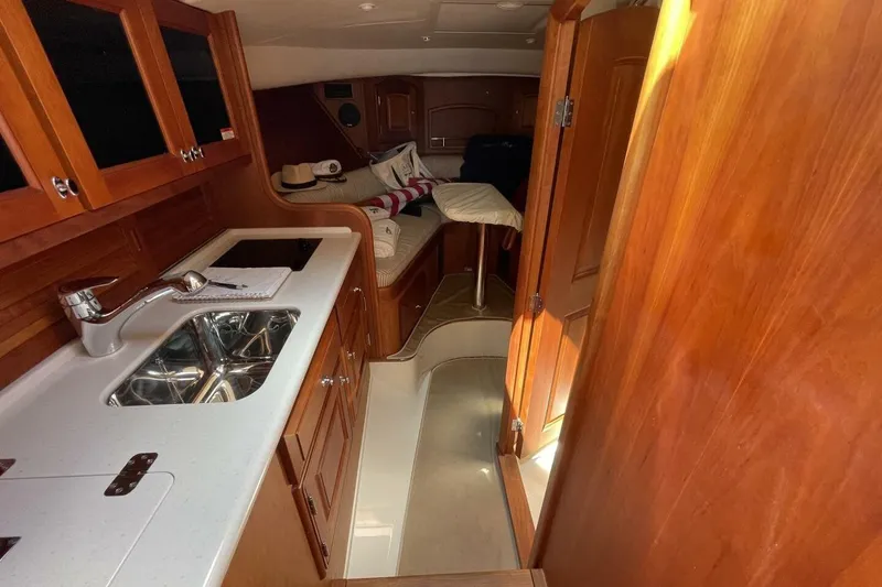 Slide: The Image of Interior of 2012 Hinckley Runabout 38, featuring wooden cabinetry and compact kitchen area. - 6
