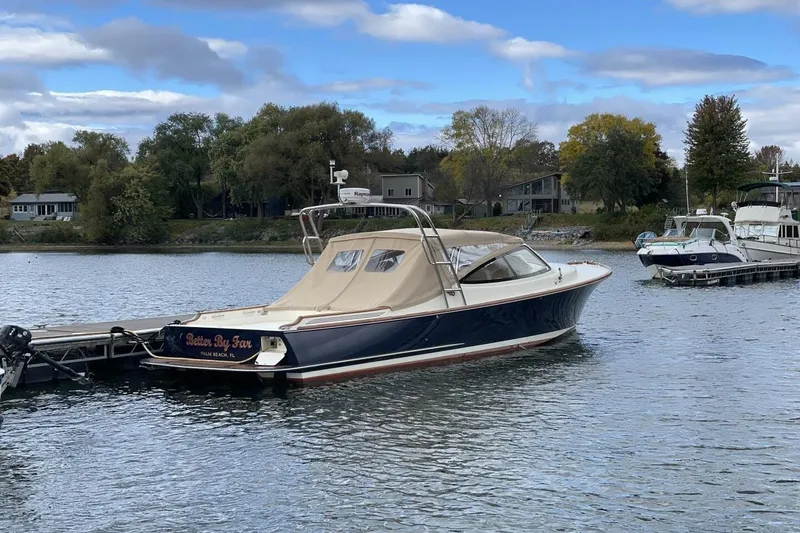 The Image of 2012 Hinckley Runabout 38 docked on a serene lake with trees in the background. - 0