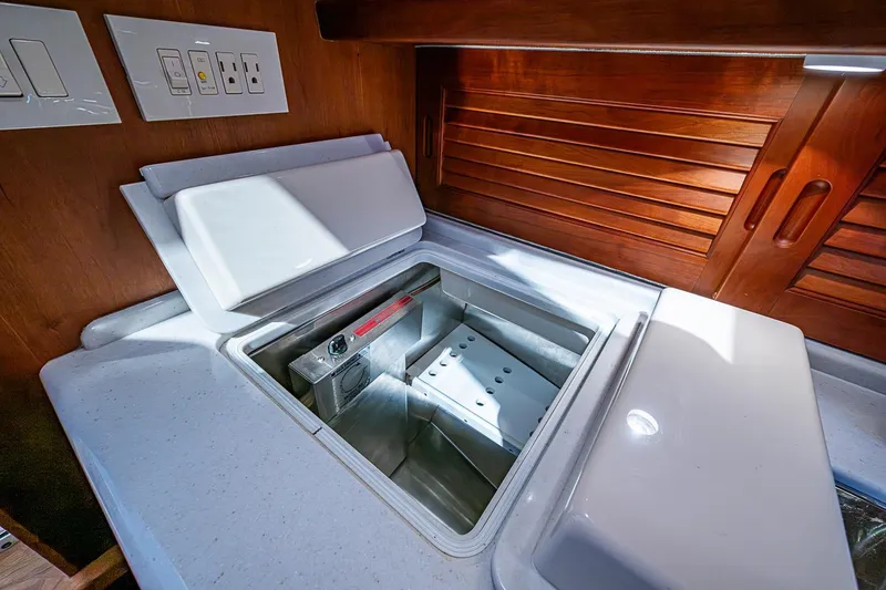 Slide: The Image of Interior of 2012 Hinckley Runabout 38 showing a built-in cooler and wooden cabinetry. - 12