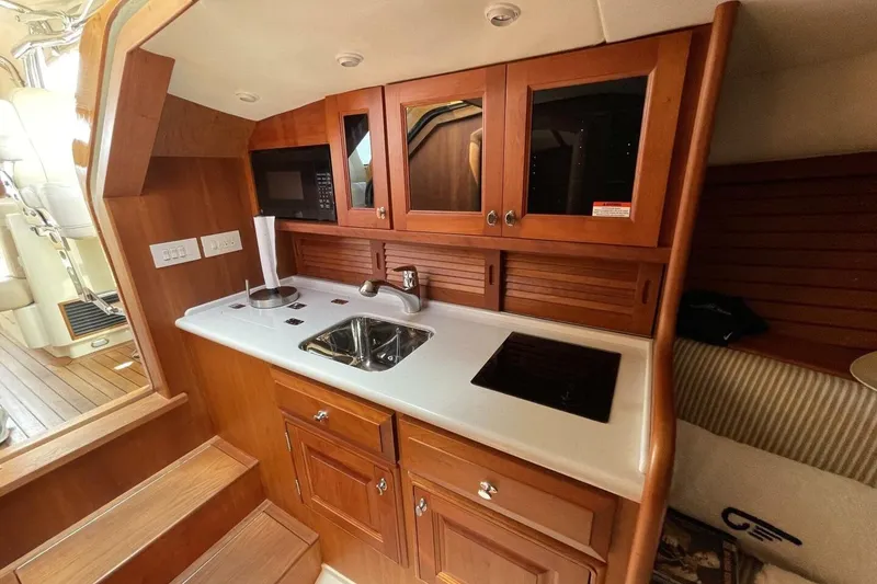 Slide: The Image of Interior of 2012 Hinckley Runabout 38, featuring a compact wooden kitchenette. - 5
