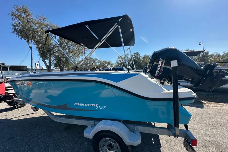 Slide: The Image of 2022 Bayliner Element M17 boat with Mercury engine on trailer, under clear blue sky. - 19