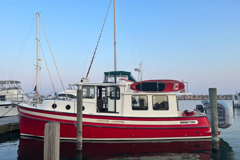 The Image of 2000 Nordic Tug 37 docked at marina, featuring red and white design. - 0