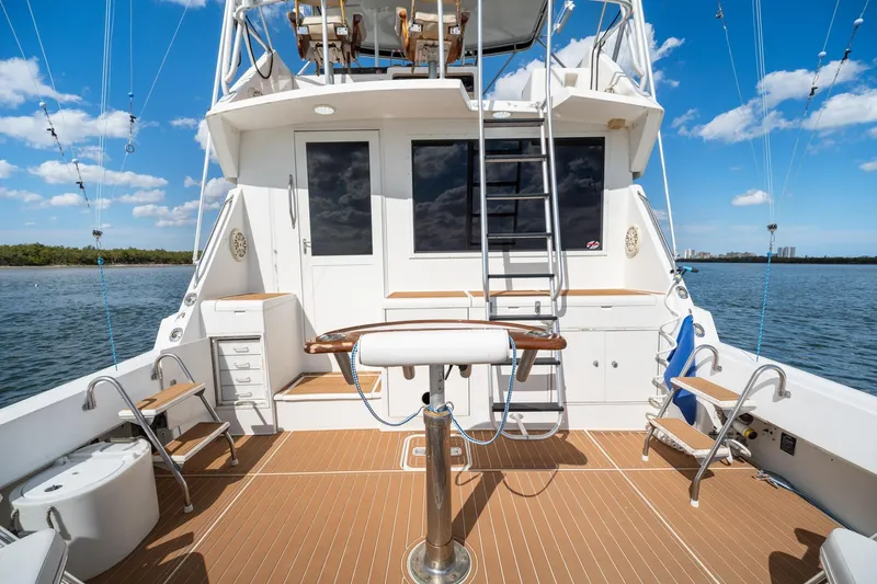 Slide: The Image of 1995 Hatteras 50 Convertible yacht deck with fishing setup, ladder, and ocean view. - 10