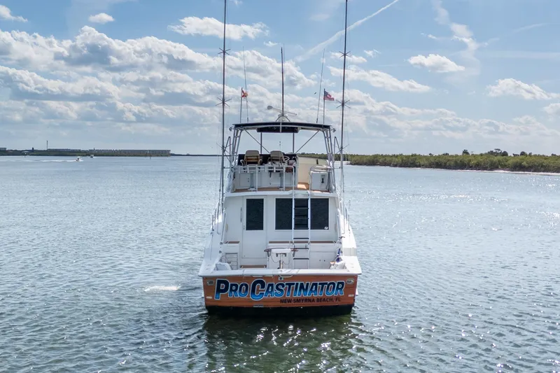 Slide: The Image of 1995 Hatteras 50 Convertible boat on water, rear view, clear sky, "Procastinator" name visible. - 4