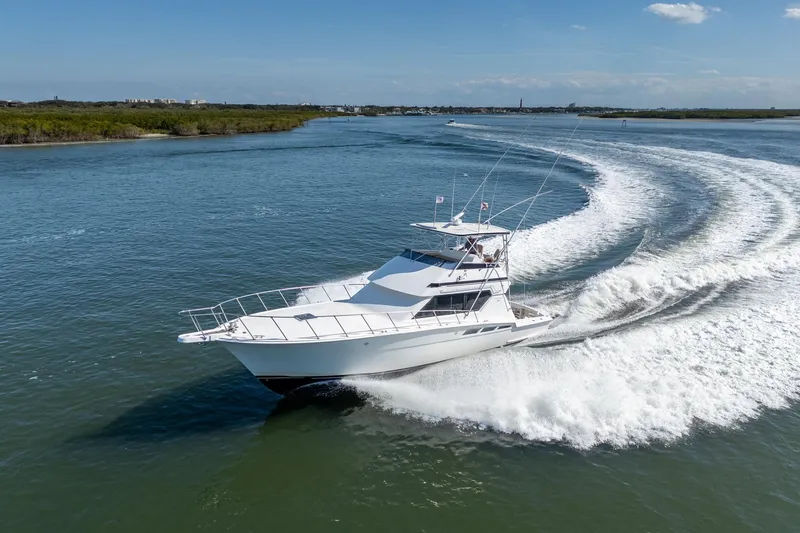 Slide: The Image of 1995 Hatteras 50 Convertible yacht cruising on open water, creating a dynamic wake. - 5