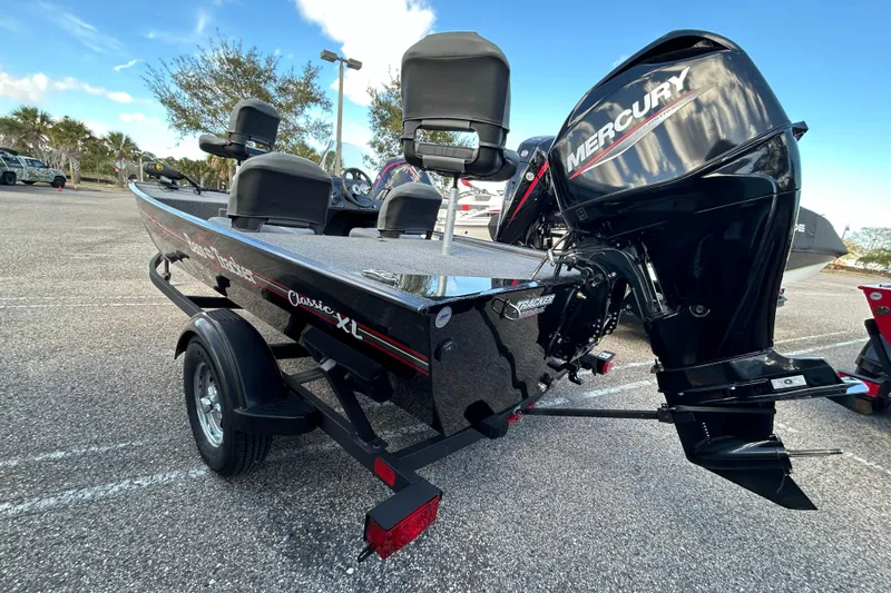 Slide: The Image of 2024 Tracker Bass Tracker Classic XL boat with Mercury engine in a parking lot. - 2