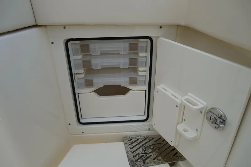 Slide: The Image of Storage compartment on a 2026 Scout 288 LXF boat, featuring organized shelves and secure latch. - 16