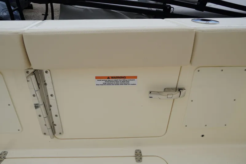 Slide: The Image of 2026 Scout 288 LXF boat interior with safety warning label and secure latch. - 62