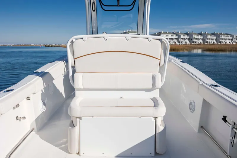 Slide: The Image of 2022 Sea Hunt Ultra 265 SE boat interior with white seating, on calm water. - 21