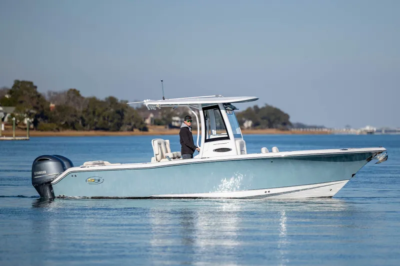 Slide: The Image of 2022 Sea Hunt Ultra 265 SE boat cruising on calm water with scenic background. - 3
