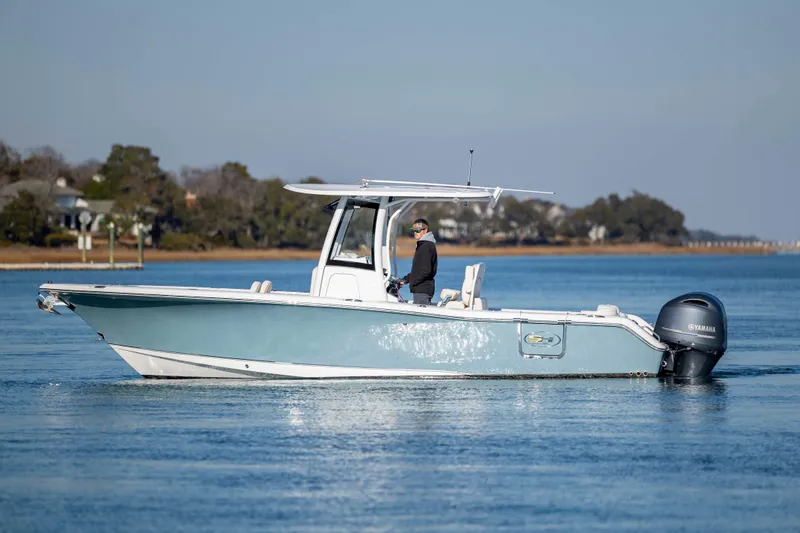 Slide: The Image of 2022 Sea Hunt Ultra 265 SE boat cruising on calm water with scenic background. - 7