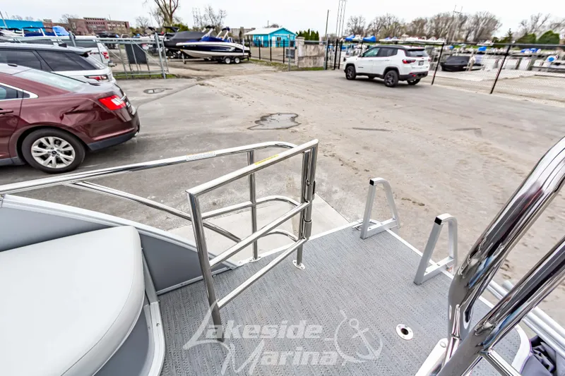 Slide: The Image of 2026 Godfrey Sweetwater 2286 SFLC pontoon boat at marina with parked cars. - 23