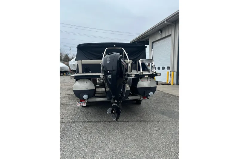 Slide: The Image of 2021 Barletta Cabrio 20UC pontoon boat with Mercury outboard motor, parked near a garage. - 3