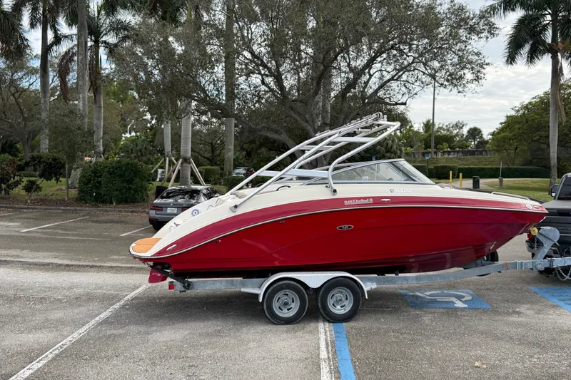 The Image of 2014 Yamaha Boats 242 Limited in red on a trailer, parked in a lot. - 0