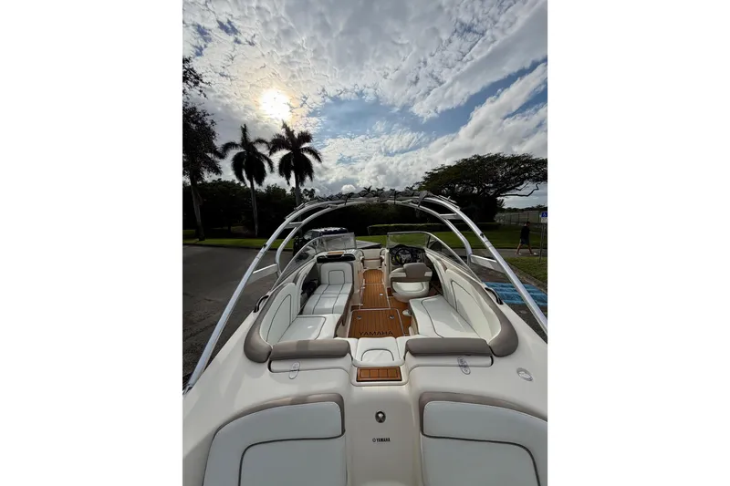 Slide: The Image of 2014 Yamaha Boats 242 Limited, sleek interior, palm trees, cloudy sky, outdoor setting. - 3
