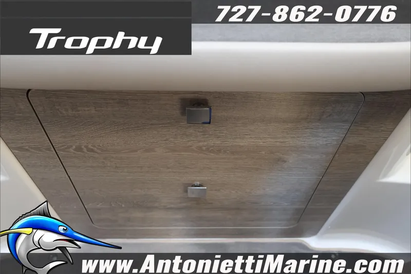 Slide: The Image of 2026 Bayliner Trophy T29 Explorer interior detail with wood finish and contact information. - 16