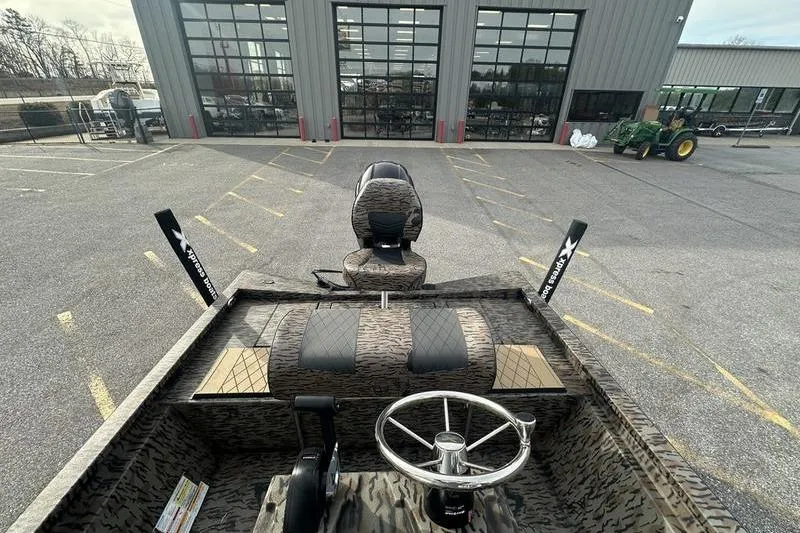 Slide: The Image of 2026 Xpress H190B Bay boat interior with steering wheel and seating, parked outside a building. - 6