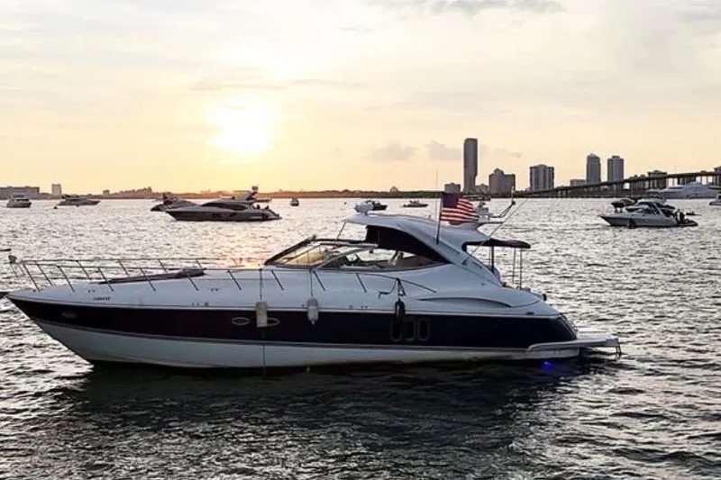 Slide: The Image of 2005 Cruisers Yachts 500 Express on water at sunset with city skyline. - 7