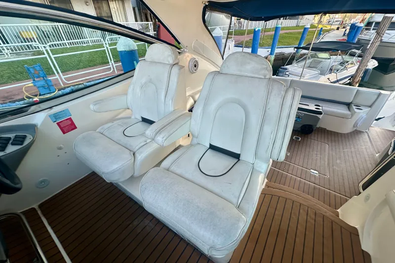 Slide: The Image of 2005 Cruisers Yachts 500 Express cockpit with white leather seats and wooden flooring. - 20