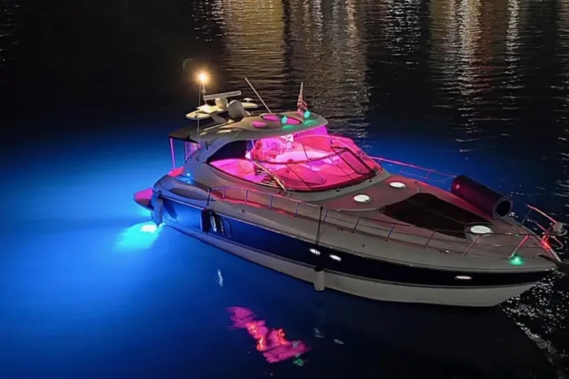 Slide: The Image of 2005 Cruisers Yachts 500 Express illuminated at night with vibrant blue and pink lights. - 8