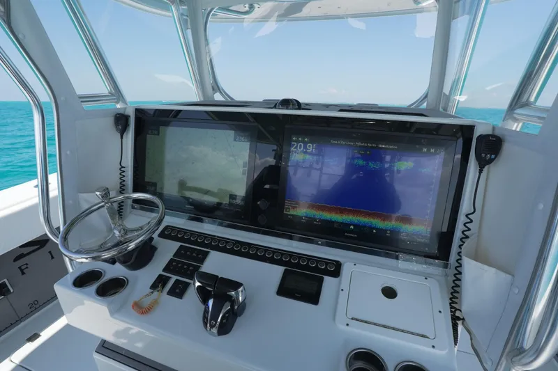 Slide: The Image of 2024 Freeman 42 boat dashboard with navigation screens and steering wheel on open water. - 22