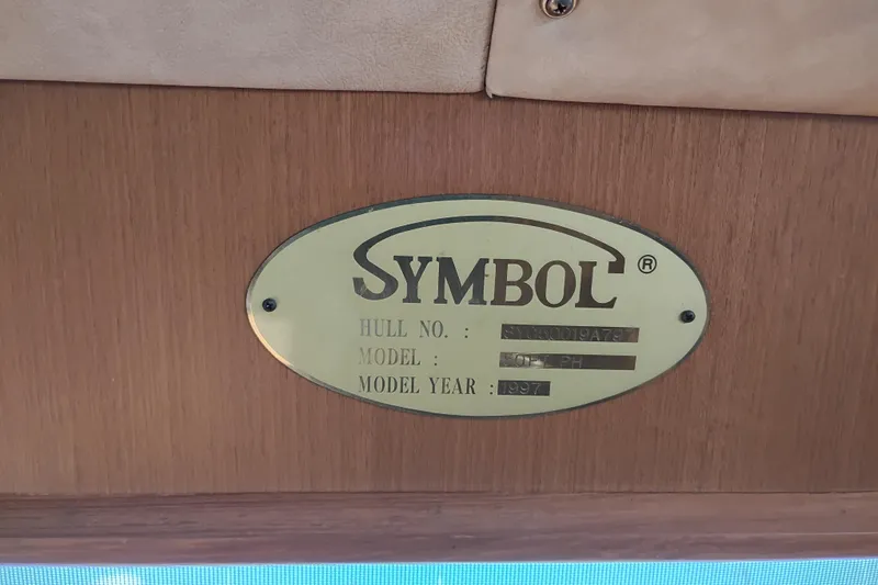 Slide: The Image of Plaque displaying "Symbol" brand, model "50 Pilothouse," year 1997, on wooden surface. - 102