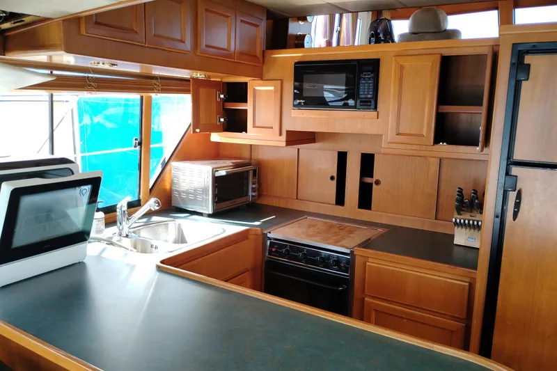 Slide: The Image of 1997 Symbol 50 Pilothouse kitchen with wooden cabinetry, modern appliances, and ample counter space. - 21