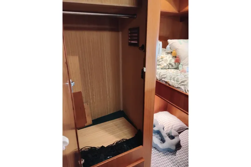 Slide: The Image of Wooden closet interior on a 1997 Symbol 50 Pilothouse yacht, adjacent to a cozy bed. - 75