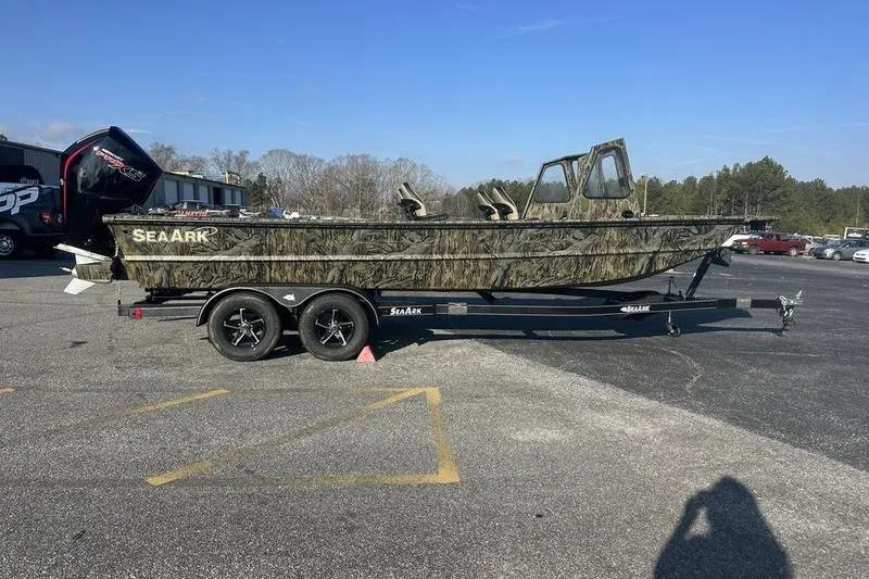 The Image of 2026 SeaArk 2272 MV boat on trailer, camo design, parked outdoors. - 0