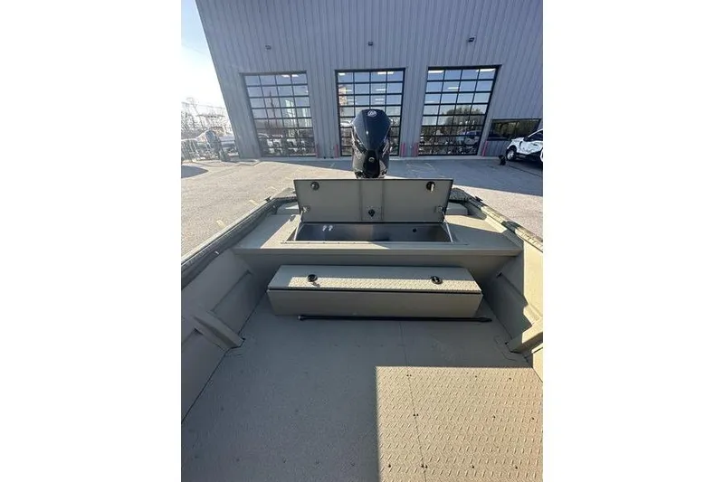 Slide: The Image of 2026 SeaArk 2272 MV boat interior with motor, parked outside a building. - 2