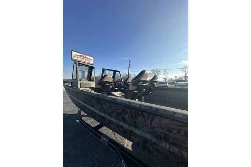Slide: The Image of 2026 SeaArk 2272 MV boat with camouflage design, parked outdoors under clear blue sky. - 7