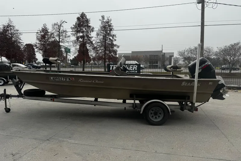 Slide: The Image of 2007 SeaArk Coastal 200 CC boat on trailer, parked outdoors with trees in background. - 7