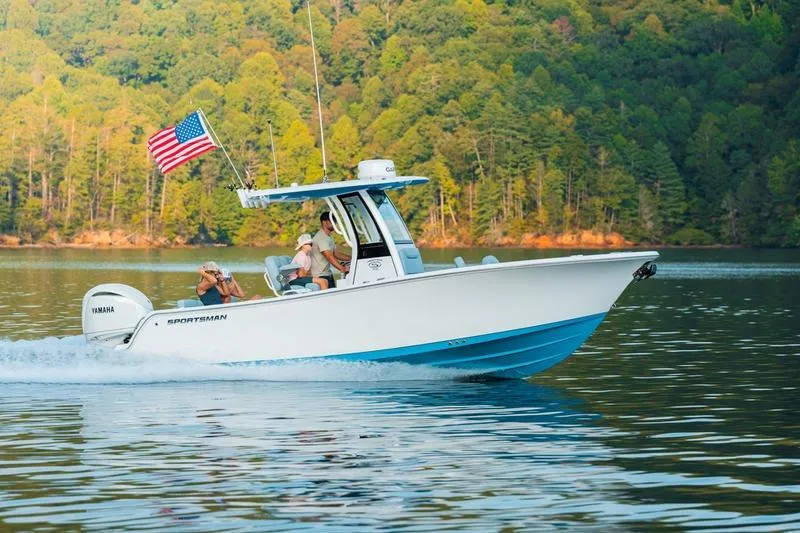 Slide: The Image of 2026 Sportsman Heritage 231 Center Console boat cruising on a scenic lake. - 2
