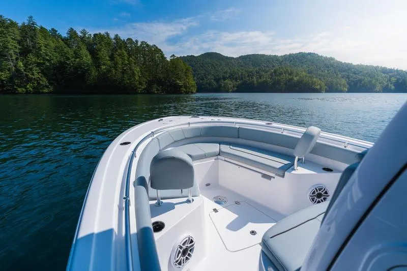 Slide: The Image of 2026 Sportsman Heritage 231 Center Console boat on a serene lake with forested hills. - 22