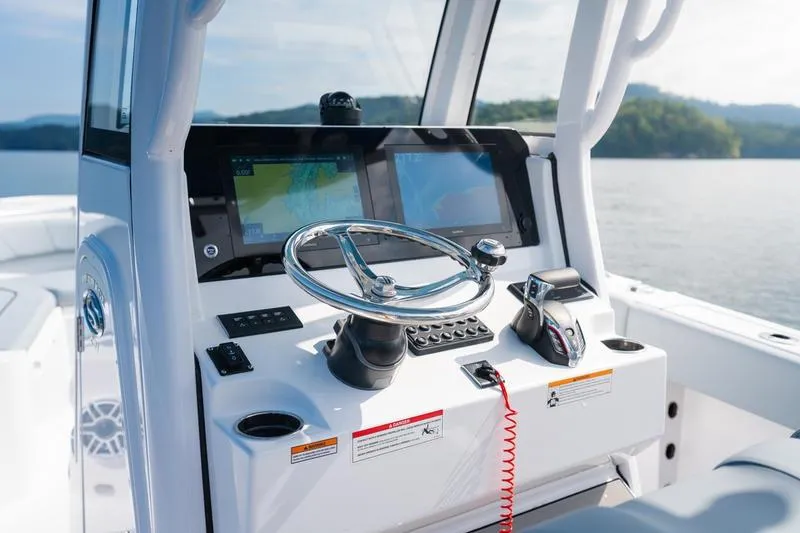 Slide: The Image of 2026 Sportsman Heritage 231 Center Console boat dashboard with steering wheel and navigation screens. - 32