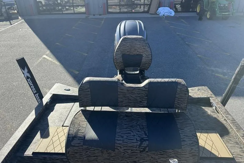 Slide: The Image of 2026 Xpress H210B Bay boat with patterned seating and motor, parked outdoors. - 7