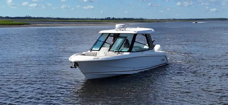 Slide: The Image of A 2026 Boston Whaler 330 Vantage cruising on calm waters under a blue sky. - 1