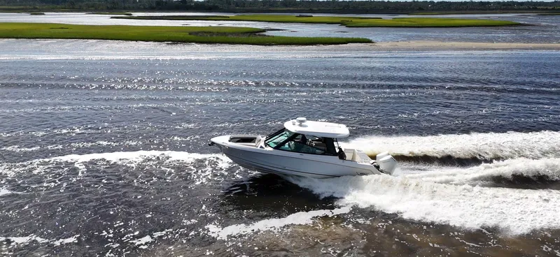 Slide: The Image of A 2026 Boston Whaler 330 Vantage speeds across the water in a scenic setting. - 10