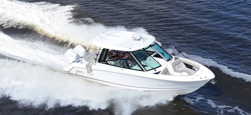Slide: The Image of A white Boston Whaler 330 Vantage boat speeds across the water, creating a large wake. - 7