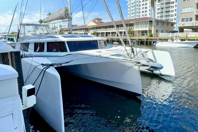 The Image of 2023 NEEL 43 trimaran docked in a marina, surrounded by modern buildings. - 1