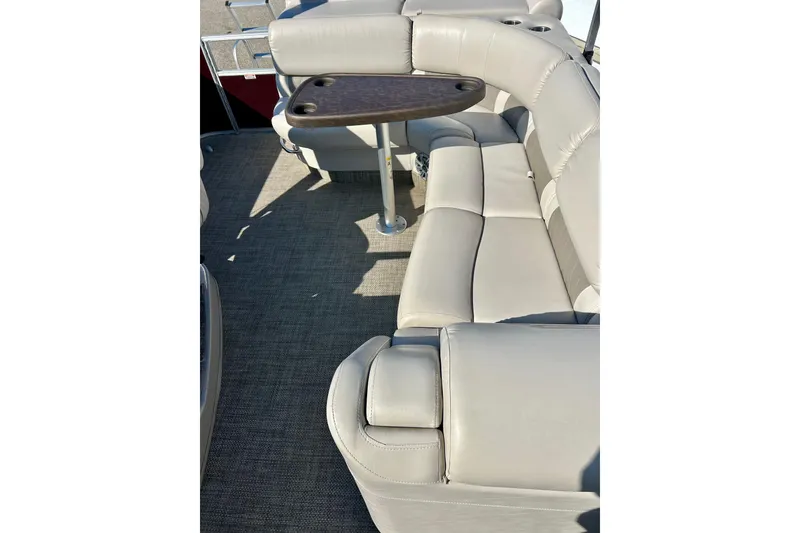 Slide: The Image of 2016 Bennington R21 boat interior with beige seating and a small table. - 12