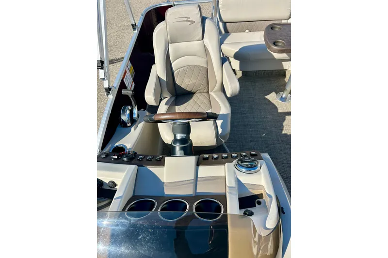 Slide: The Image of Captain's seat and console of 2016 Bennington R21 boat, featuring controls and cup holders. - 13