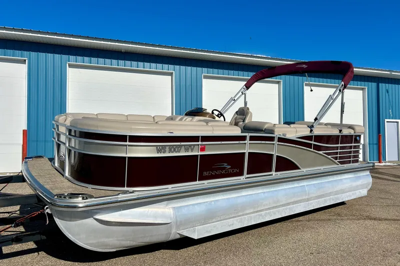 Slide: The Image of 2016 Bennington R21 pontoon boat with maroon accents, parked near blue building. - 24