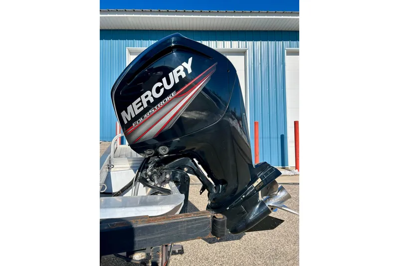 Slide: The Image of Mercury FourStroke engine on 2016 Bennington R21 boat, parked near blue building. - 30