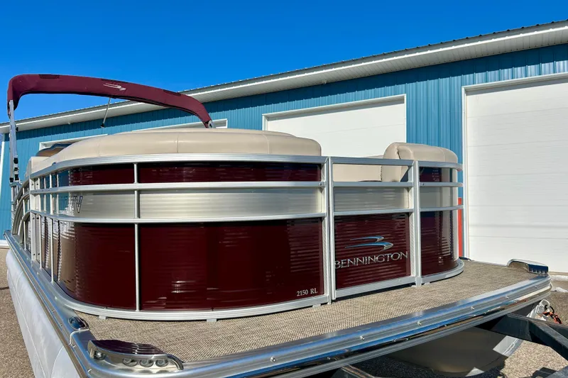 Slide: The Image of 2016 Bennington R21 pontoon boat with maroon exterior, parked near blue building. - 6