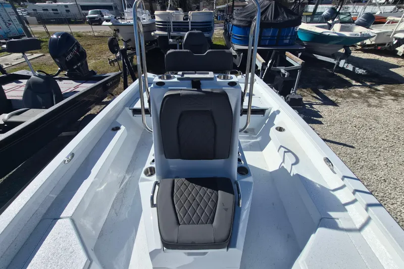 Slide: The Image of 2026 Xpress H20B Bay boat interior with seating and console, parked outdoors. - 9