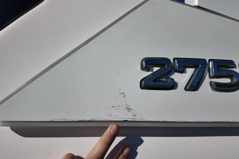 Slide: The Image of 2024 Yamaha Boats 275SE emblem with visible scratches and a pointing finger. - 19